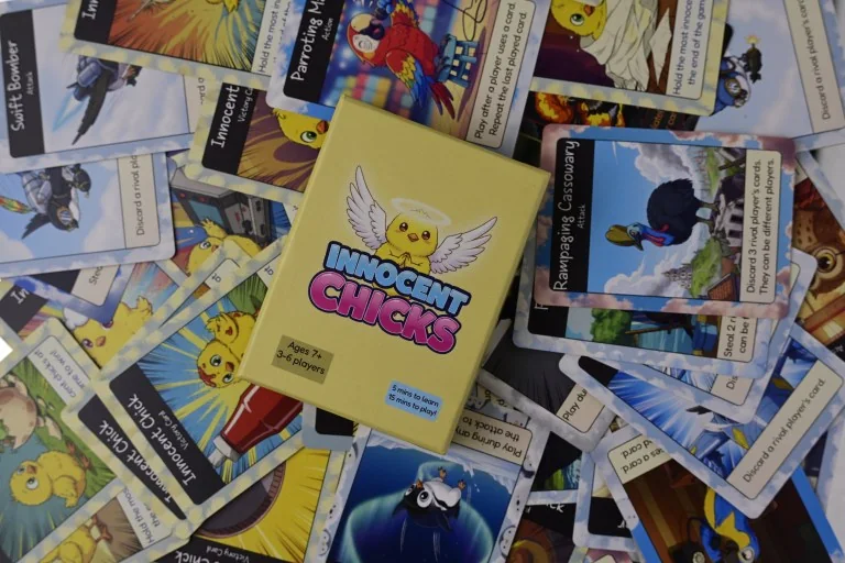 The Innocent Chicks card deck box surrounded by spread-out bird cards: Swift Bomber, Parroting Macaw, Rampaging Cassowary and more.
